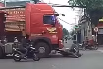 Người bán dừa đi xe máy thoát chết dù bị cuốn vào gầm container