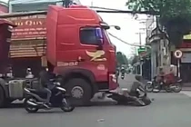 Người bán dừa đi xe máy thoát chết dù bị cuốn vào gầm container
