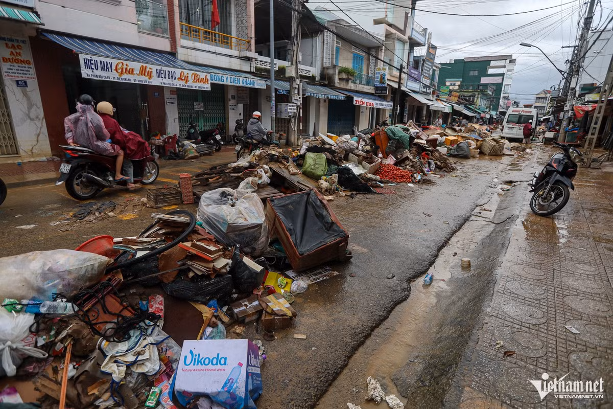 Rác thải phủ kín đoạn đường quanh khu chợ Thành, phường Diên Khánh. Đây vốn là khu chợ tấp nập, nhưng sau trận ngập, hàng loạt hoa quả và rau trái của tiểu thương bị hư hỏng, theo dòng nước dồn lại thành từng đống lớn. Mặt đường ngổn ngang rác và nông sản thối, khiến việc đi lại và dọn dẹp của người dân càng thêm khó khăn.