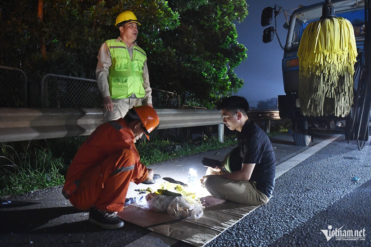 Nhóm công nhân một công ty quản lý đường bộ thay phiên nhau túc trực khu vực đầu đoạn ngập đã hai ngày nay.