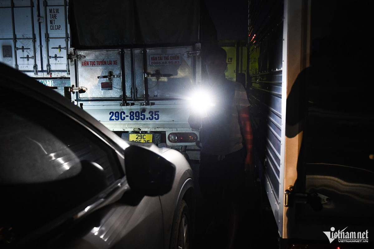 Tại đoạn khô ráo đầu đoạn ngập, nhiều xe tải nhỏ, ô tô phân khúc sedan, thậm chí cả CUV, SUV gầm cao cũng được chủ xe cho dừng chờ nước rút thêm. Một tài xế dùng đèn pin đi lại ngó nghiêng tình hình ngập lụt.