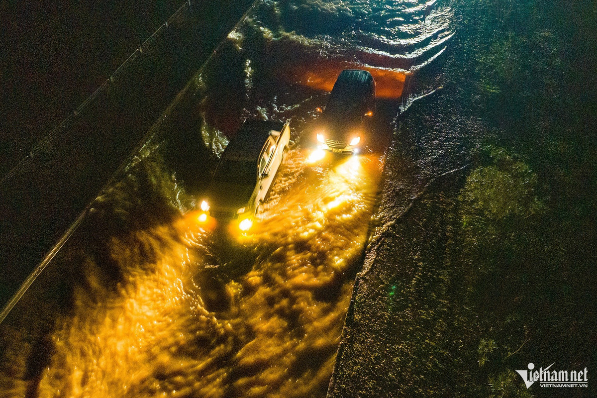 Một chiếc ô tô gầm cao khi bắt đầu "lội" nước được khoảng 30 mét thì dừng lại vài phút. Xe đi sau phải đánh lái sang bên phải vượt lên.