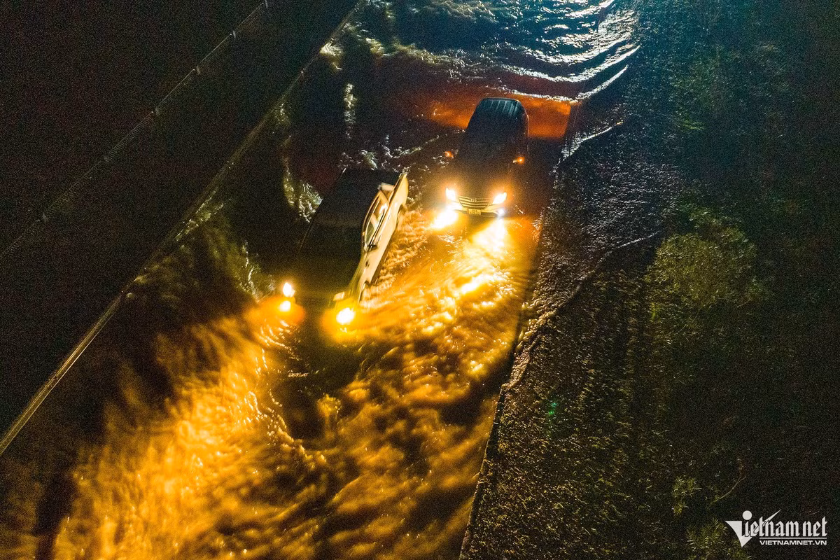 Một chiếc ô tô gầm cao khi bắt đầu "lội" nước được khoảng 30 mét thì dừng lại vài phút. Xe đi sau phải đánh lái sang bên phải vượt lên.