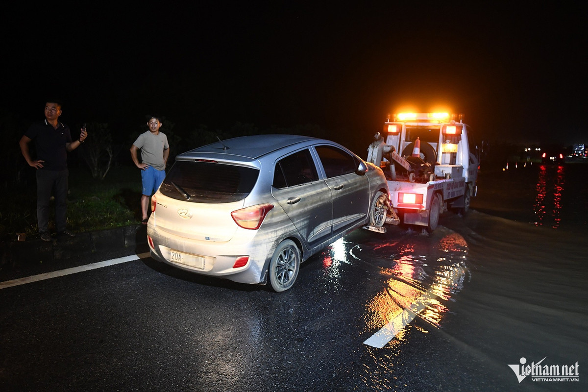 Dọc đường về Hà Nội, xe cứu hộ kéo ô tô bị ngập nước liên tục nối đuôi nhau phóng qua làn nước.