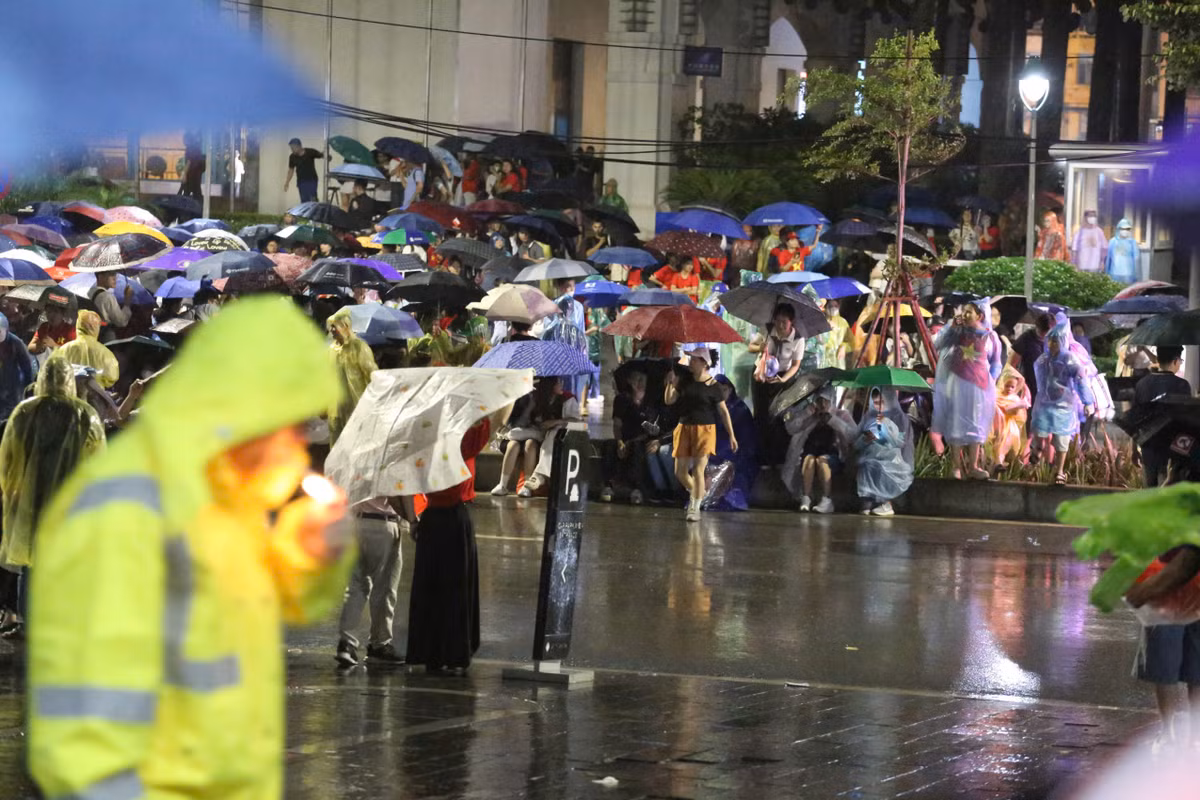 Người dân nghiêm ngắn xếp hàng trong cơn mưa nặng hạt.