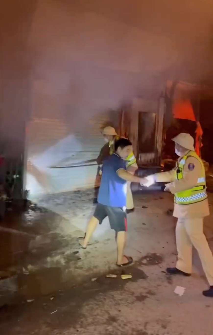 CSGT cùng người dân phá cửa, hỗ trợ giải cứu 11 người trong 2 nhà ra ngoài an toàn trước khi lửa khói bịt kín các lối thoát hiểm.