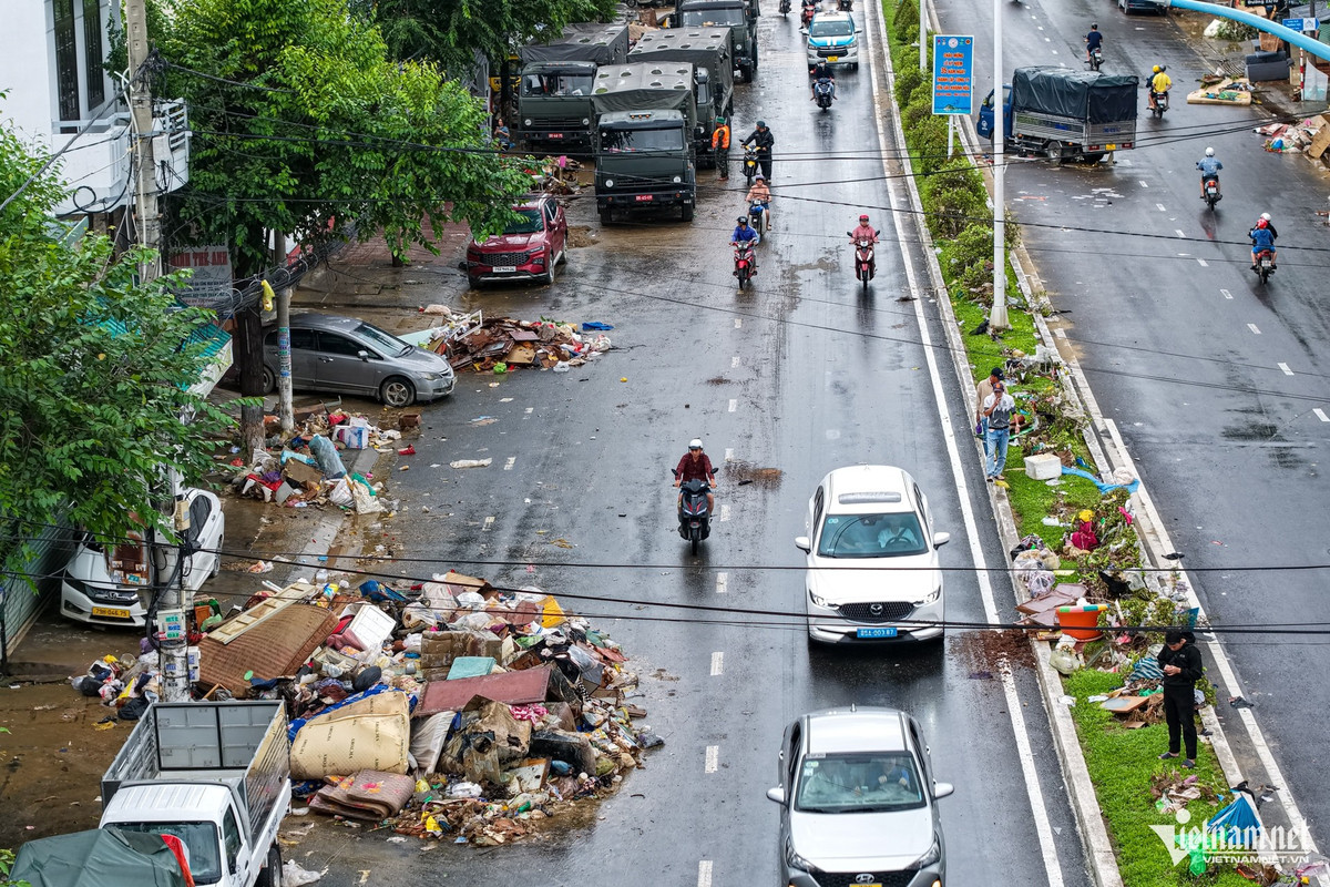 Dọc đường 23/10, rác thải sau lũ ken đặc thành từng mảng dài, tràn ra gần nửa mặt đường và phủ kín dải phân cách. Các đơn vị dọn dẹp cùng người dân miệt mài thu gom, chờ từng xe rác chuyển đi nhưng lượng rác tồn đọng quá lớn khiến tuyến đường vẫn ngổn ngang.