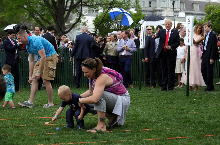 Tổng thống Trump, Đệ nhất phu nhân Melania và con trai Barron đứng xem các bậc phụ huynh trợ giúp con của họ chơi trò chơi tại bãi cỏ phía nam của Nhà Trắng trong dịp lễ Phục sinh.