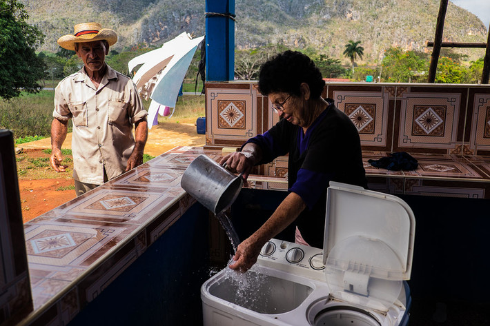 Người phụ nữ ở Vinales phải tự đổ nước vào máy giặt mới có thể sử dụng. Ảnh: Al Jazeera