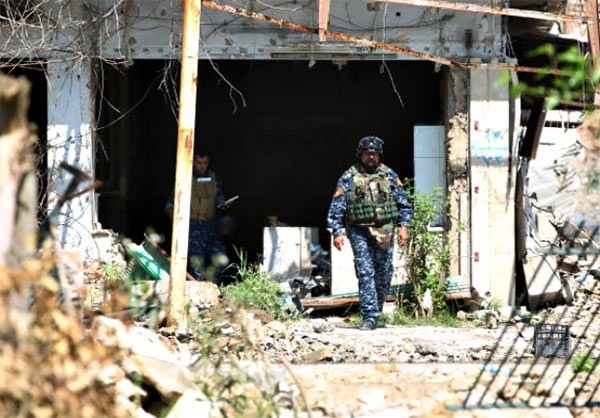 Lực lượng Iraq tham gia chiến dịch giải phóng thành phố Mosul đi qua một ngôi nhà đổ nát ở khu vực thành cổ. Ảnh: FNA.