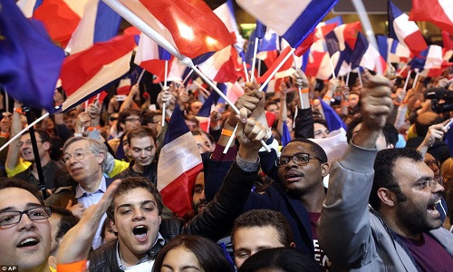 Những người ủng hộ ông Macron vẫy cờ hò reo sau khi ứng viên trung dung chiến thắng trong vòng 1 bầu cử. Ảnh: AP.