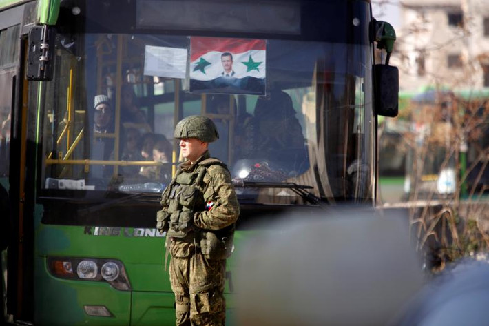 Lính Nga đứng gần một chiếc xe buýt đang chở dân thường Syria trở về nhà của họ ở Hanono, tỉnh Aleppo, hồi tháng 12/2016.