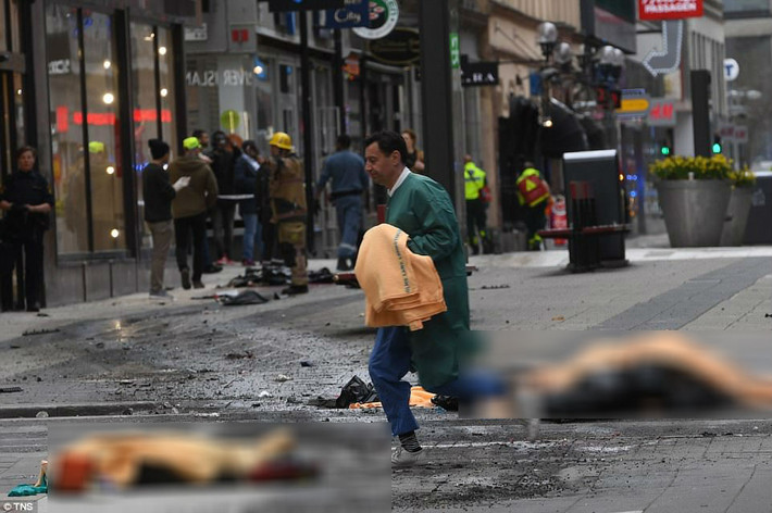 Nhân viên y tế phủ những tấm chăn màu da cam lên các thi thể bên ngoài trung tâm Ahlens ở Klarabergsgatan. Ảnh: Daily Mail.