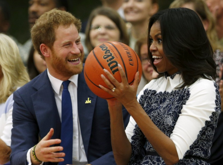 Hoàng tử Harry cười lớn khi Đệ nhất phu nhân Mỹ Michelle Obama bắt được một quả bóng rổ trong lúc xem trận đấu ở Fort Belvoir, bang Virginia, Mỹ, ngày 28/10/2015. Ảnh: WP.