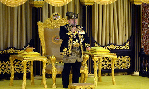 Sultan Muhammad V hôn lên thanh bảo kiếm. Ông đeo dây đai thêu hoa văn bằng ren vàng và mang các vật trang trí của hoàng gia làm bằng vàng, ngọc bích và ngà voi. Ảnh: Bernama.