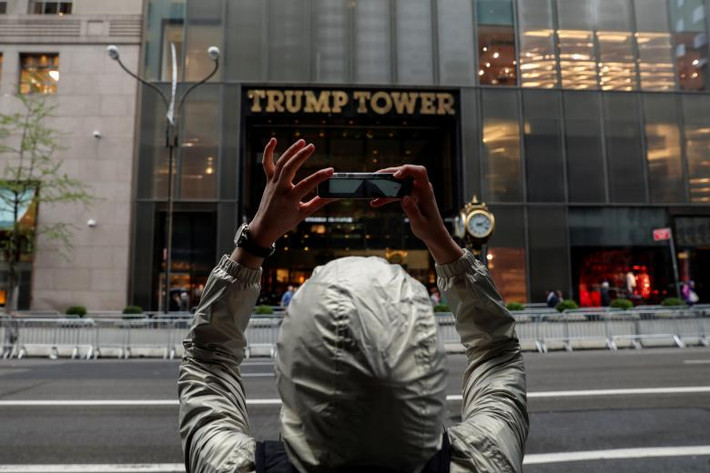 Người phụ nữ dùng điện thoại di động chụp bên ngoài tòa Tháp Trump. Được biết, Đệ nhất Phu nhân Mỹ Melania Trump và con trai, Barron Trump, vẫn đang sống trong tòa tháp này. (Nguồn ảnh: Reuters)