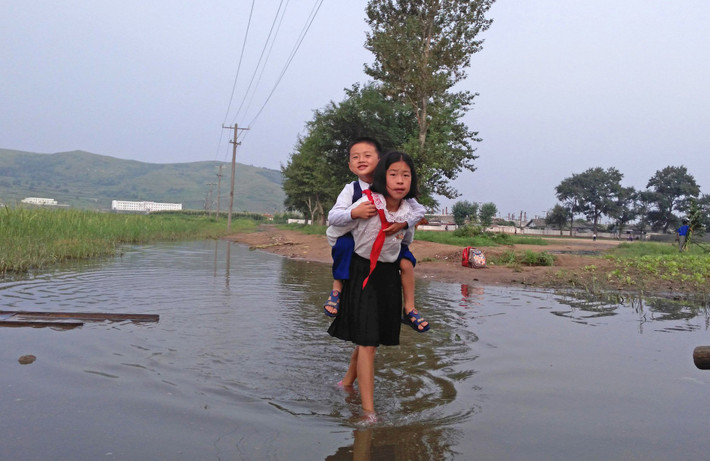 Bé gái cõng em đến trường qua con đường ngập nước ở Tumangan, Triều Tiên, hồi tháng 8/2015.