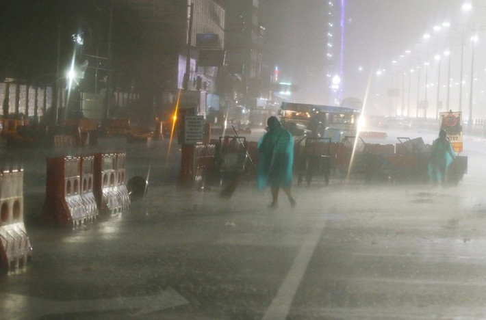 Các nhân viên vệ sinh làm việc dưới trời mưa bão ở Manila sáng 15/9. Ảnh: AP.