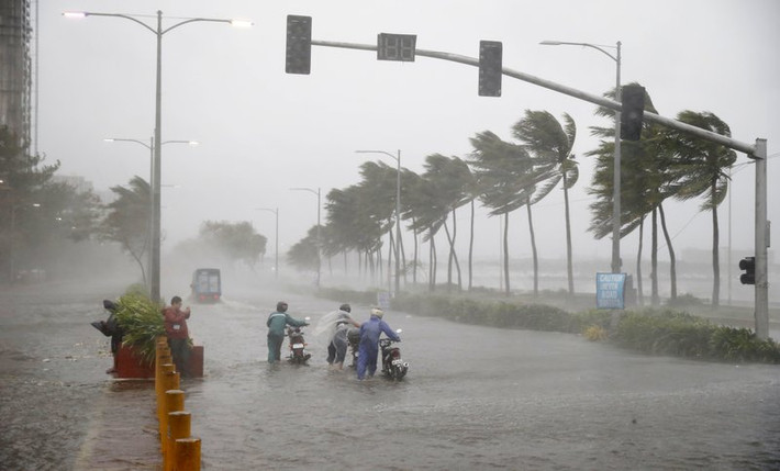 Người dân phải dắt xe đi qua con phố ngập lụt dưới trời mưa bão ở Manila, Philippines, hôm 15/9. Ảnh: AP.