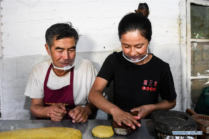 Ông Chang Sanwen, 65 tuổi, đang hướng dẫn con gái mình làm bánh trung thu tại cửa hàng của ông ở Phong Trấn ngày 18/9.