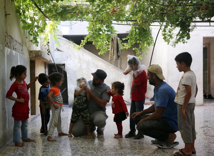 Một bé trai được hướng dẫn cách đeo mặt nạ phòng độc ở Idlib. Được biết, khoảng 3 triệu dân thường đang sống trong thành trì của phiến quân ở Tây Bắc Syria, bao gồm hầu hết tỉnh Idlib và một số khu vực ở Latakia, Hama và Aleppo.