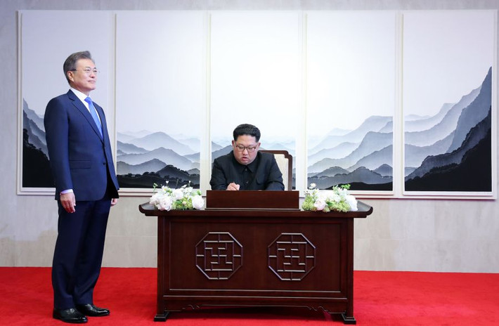 Lãnh đạo Triều Tiên Kim Jong-un viết lưu bút tại Nhà Hòa Bình ở làng Bàn Môn Điếm trong khi Tổng thống Hàn Quốc Moon Jae-in đứng bên cạnh. Ảnh: Getty.