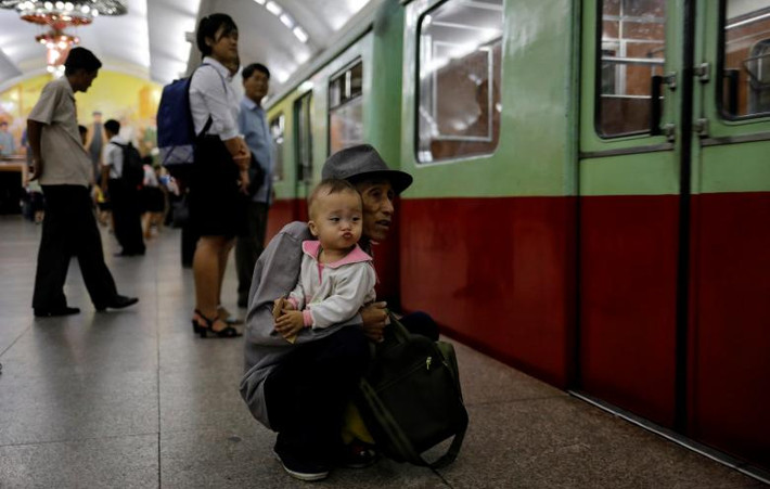 Người đàn ông ôm cháu chờ lên tàu điện ngầm tại một nhà ga ở thủ đô Triều Tiên.