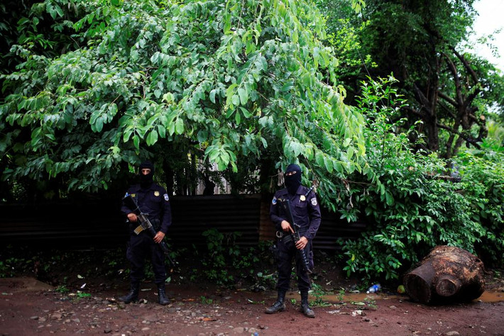 Cảnh sát El Salvador đứng gác bên ngoài một ngôi nhà trong khi người dân sơ tán khỏi làng El Castano.