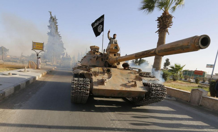 Các chiến binh IS đứng trên xe tăng diễu hành qua đường phố Raqqa ngày 30/6/2014.