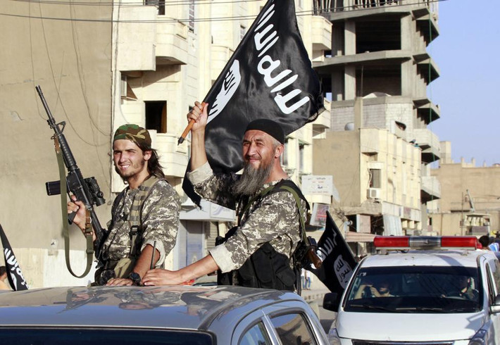 Các chiến binh IS cầm vũ khí và cờ trên đường phố Raqqa.