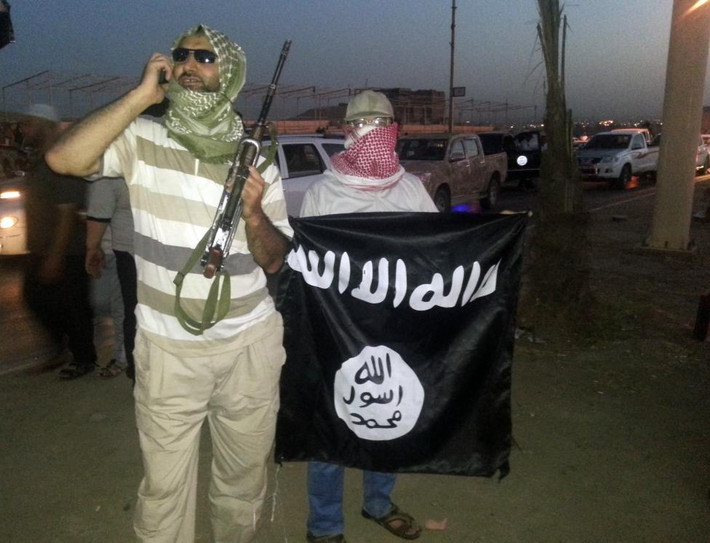 Hai chiến binh IS cầm cờ và vũ khí ở thành phố Mosul, Iraq, ngày 23/6/2014.