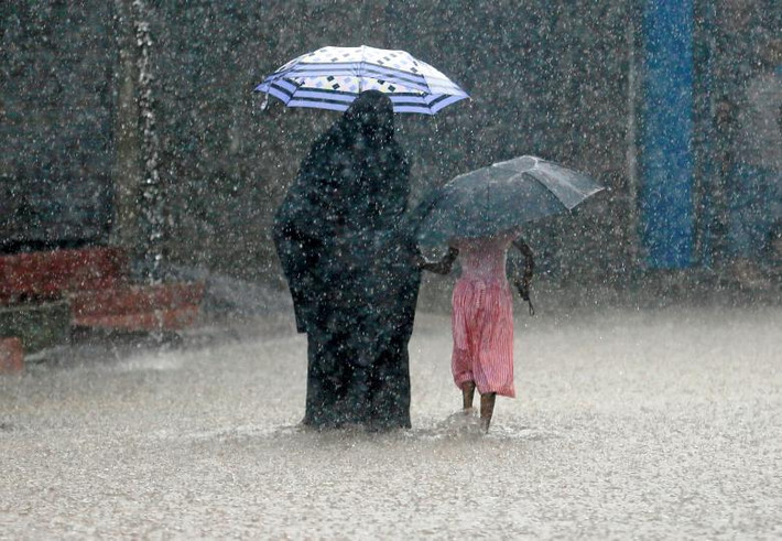 Một phụ nữ đi cùng bé gái qua con đường ngập lụt dưới trời mưa ở Malwana, Sri Lanka, ngày 23/5.