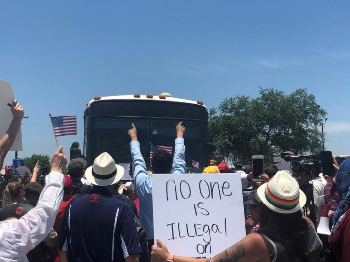 Đám đông đứng trước một chiếc xe buýt chở người nhập cư gần cơ sở giam giữ McAllen ở Texas ngày 23/6.