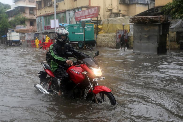 Người đàn ông đi qua con đường ngập nước ở Mumbai ngày 25/6/2018.