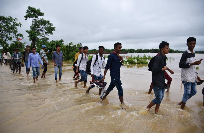 Mọi người đi qua đoạn đường cao tốc bị ngập nặng ở huyện Golaghat, Assam, ngày 13/6.