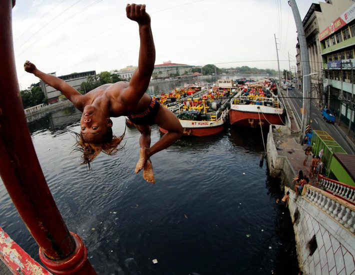 Một em nhỏ nhảy xuống dòng sông đen ngòm ở Philippines.
