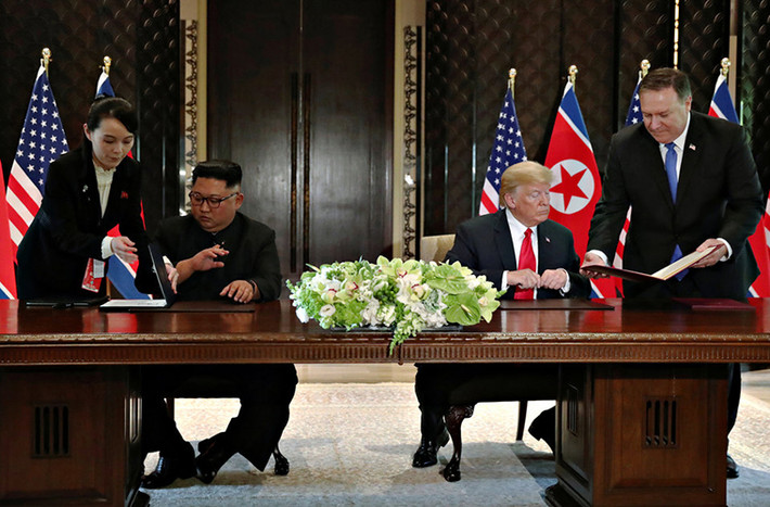 Bà Kim Yo Jong đứng bên cạnh anh trai, lãnh đạo Kim Jong-un, khi hai nhà lãnh đạo Mỹ - Triều chuẩn bị ký Tuyên bố chung sau cuộc hội đàm thượng đỉnh tại khách sạn Capella, Singapore, hôm 13/6.