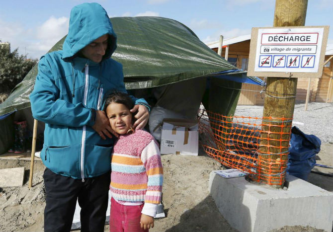 Hai bố con tị nạn người Syria đứng trước túp lều của họ ở thành phố Calais, Pháp ngày 19/9.