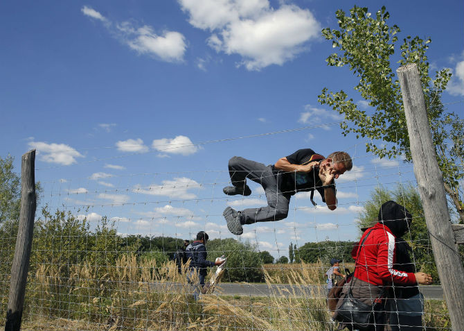 Một di dân trèo qua hàng rào bảo vệ trên đường ở làng Roszke, Hungary ngày 9/9.