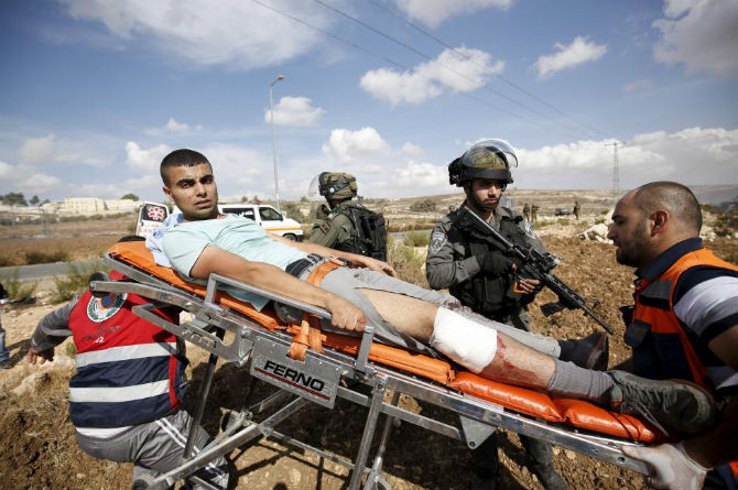 Các nhân viên y tế đưa một người Palestine bị thương trong cuộc xung đột giữa người biểu tình Palestine và binh sĩ Israel tại thánh đường Jerusalem tới bệnh viện.