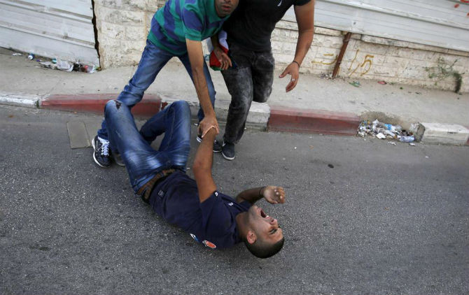 Một người Palestine ngã trên đường sau bị khi trúng đạn trong cuộc đụng độ với binh sĩ Israel.
