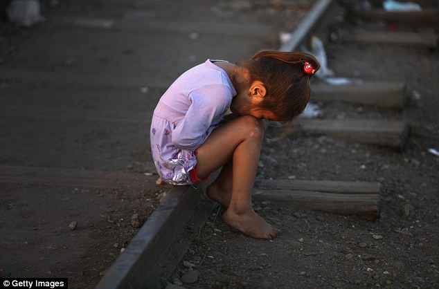 Một bé gái Syria ngồi trên đường ra tàu tại biên giới Serbia – Hungary cùng gia đình chờ đến khi trời tối để vượt biên.