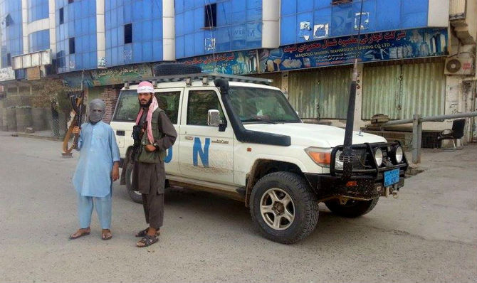 Hai chiến binh Taliban đứng gần một chiếc xe của Liên Hợp Quốc tại thành phố Kunduz.