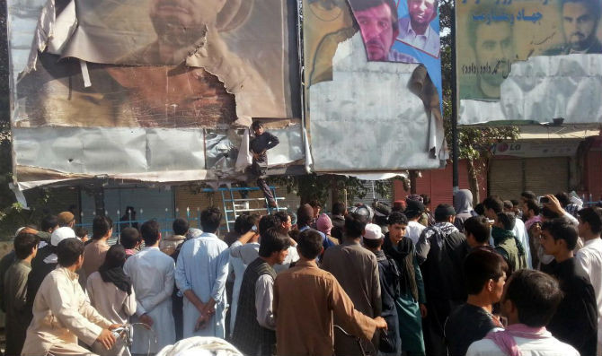 Một người ủng hộ Taliban gỡ những bức ảnh của các nhà lãnh đạo tại quảng trường chính ở Kunduz ngày 29/9.