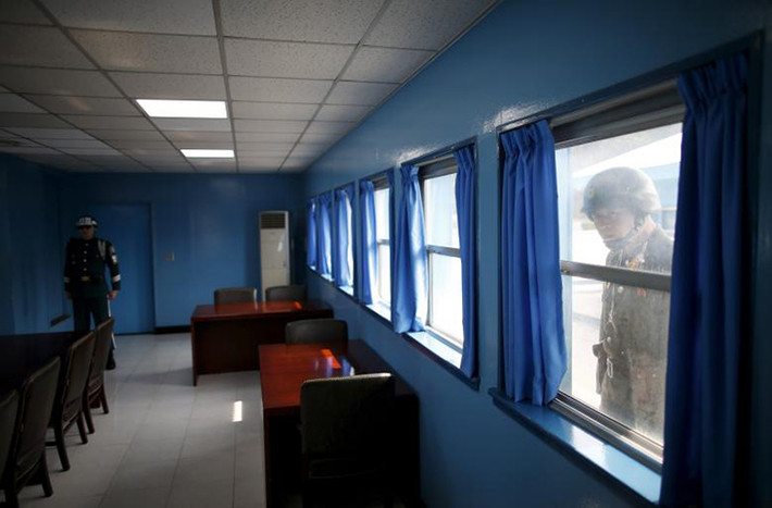 Binh sĩ Triều Tiên ngó vào một phòng họp nơi một người lính Hàn Quốc đang đứng gác tại làng Bàn Môn Điếm hồi tháng 3/2016. Ảnh: Reuters.