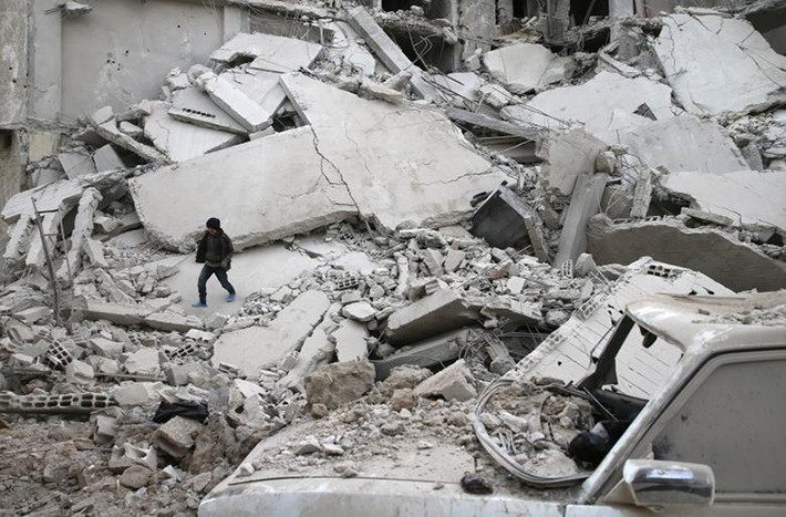 Bé trai đi qua những tòa nhà bị đổ sập tại thị trấn Misraba, Syria, ngày 4/1.