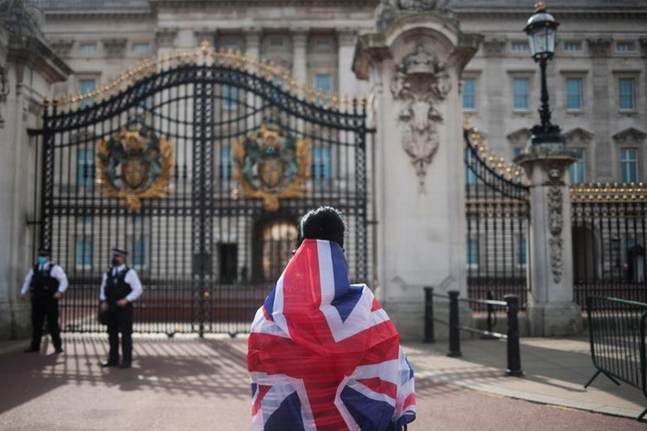 Một người dân choàng lá cờ lên người và nhìn về phía Cung điện Buckingham.