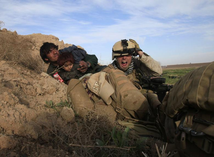Trong ảnh là Chris Sanderson, một quân nhân Mỹ, đang cố gắng bảo vệ một người đàn ông và em nhỏ Afghanistan sau khi phiến quân Taliban nổ súng ở thị trấn Marjah, Nad Ali, tỉnh Helmand, ngày 13/2/2010.