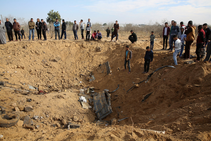 Người dân Palestine đứng nhìn một cái hố khổng lồ xuất hiện sau vụ oanh kích của Israel ở phía đông Khan Younis, miền nam Dải Gaza. Ảnh: AP.