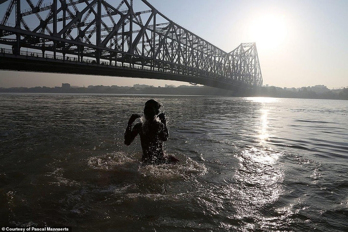 Bé trai tắm sông ở Kolkata, Ấn Độ, khi mặt trời vừa lên.